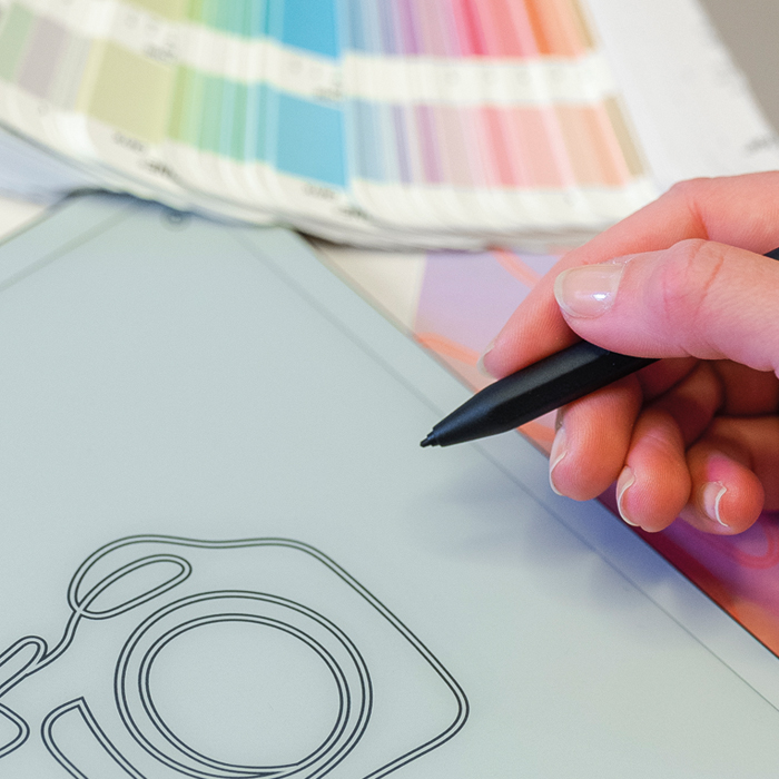 Tenk design. En person holder en penn over en brosjyre og fargeprøver. Foto