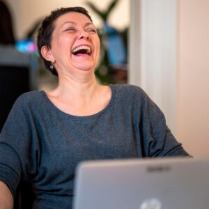 kvinne som ler foran datamaskinen